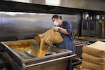 Three Sisters Nixtamal Kitchen Coordinator Blanca Luján pours corn into nixtamalization tanks in Portland, Ore., on July 20, 2022.