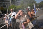 FILE - Tourists enjoy cooling off at a public water fountain In Paris, on June 26, 2026.