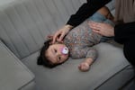 Soha Sakallah tries to coax her granddaughter, Mariam, to sleep on the sofa.