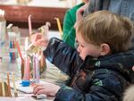 Child lighting candles at Washington Hebrew Congregation's Hanukkah celebration