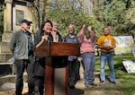 Helen Ying, president of Lone Fir Cemetery Foundation, speaks at the podium during the Qingming event the organization hosts at Lone Fir Cemetery in Portland, Ore., on April 4, 2026, with fellow board members (from left to right) Marcus Lee, John Laursen, Karin Hansen, Rachel Essig and David Dahl in the background.