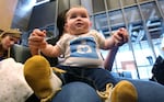 Johanna Goldhammer, 6 months, sits on the lap of her mother, Camie Goldhammer, chairman of the Native American Breastfeeding Coalition, as they listen to others testify about breastfeeding before the Seattle City Council Monday, April 9, 2012, in Seattle.