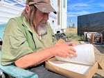 Jon Stoneman, 68, flips through some of his writing at his trailer in Redmond on Aug. 20, 2024. Stoneman is among many people who experience houselessness as housing prices surge across Central Oregon.