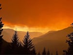 Smoke turns the morning light orange on Saturday in this photo taken near the Huckleberry Lookout, provided by the Cedar Creek Fire Incident Command.