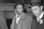 FILE — Muhammad Aziz a suspect in the slaying of Malcolm X, is escorted by detectives at police headquarters, after his arrest, in New York, Feb. 26, 1965. Aziz, previously known as Norman 3XButler, one of two men convicted in the assassination of Malcolm X, is set to be cleared after more than half a century, with prosecutors now saying authorities withheld evidence in the civil rights leader's killing, according to a news report Wednesday, Nov. 17, 2021.