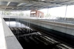 A dark stream of water flows through a concrete pool underneath the canopy.