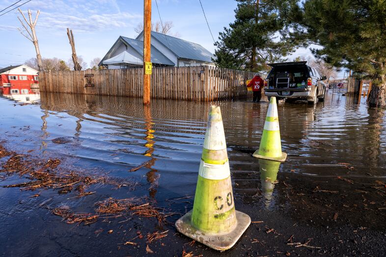 A homeowner moves personal belongings to her vehicle along Riverside Drive in Burns, Ore., March 30, 2025. 