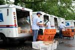In this July 31, 2020, file photo, letter carriers load mail trucks for deliveries at a U.S. Postal Service facility in McLean, Va. A U.S. judge on Thursday, Sept. 17, 2020, blocked controversial Postal Service changes that have slowed mail nationwide. The judge called them "a politically motivated attack on the efficiency of the Postal Service" before the November election.
