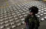 A Colombian Army soldier stands next to packages of seized cocaine during a press conference at a Military Base in Bahia Solano, department of Choco, Colombia, on March 14, 2015.