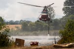 FILE - A firefighting helicopter leaves after refilling water from a pond west of Friend, Ore., to fight the Grasshopper Fire during a tour of the wildfire on Aug 3, 2026.