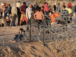 Immigrants wait near the U.S.-Mexico border fence this week in El Paso, Texas. The city has declared a state of emergency to access federal funding to house and feed the droves of new arrivals expected with the end of Title 42.