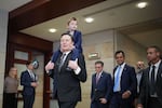 This photo shows Tesla CEO Elon Musk with his young son riding on his shoulders inside the U.S. Capitol. Walking in a rough row behind him are several men wearing suits, including businessman Vivek Ramaswamy and House Speaker Mike Johnson.