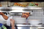 FILE - Cook Alex Romero looks out from the kitchen at the Skillet Diner in Seattle in this March 31, 2015 photo. Cooks and other employees in Washington state will earn more than $17 an hour in 2026.