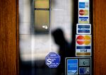 Credit card logos are seen on a downtown storefront as a pedestrian passes in Atlanta in 2012.