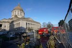 Members of the Washington National Guard stand along a perimeter fence as an Olympia Fire Dept. truck passes by, Sunday, Jan. 10, 2021, at the Capitol in Olympia, Wash.