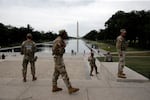 Members of the National Guard patrol as National Park Service workers clean algae from the Lincoln Memorial Reflecting Pool in Washington, D.C.