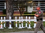 A police officer walks past a makeshift memorial for the shooting victims at Robb Elementary School in Uvalde, Texas, on May 26. The shooter in the attack legally purchased a gun before he turned 21.