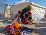 Syrians warm up by a fire at a make-shift shelter for people who were left homeless, near the rebel-held town of Jindayris on Feb. 8, 2023.