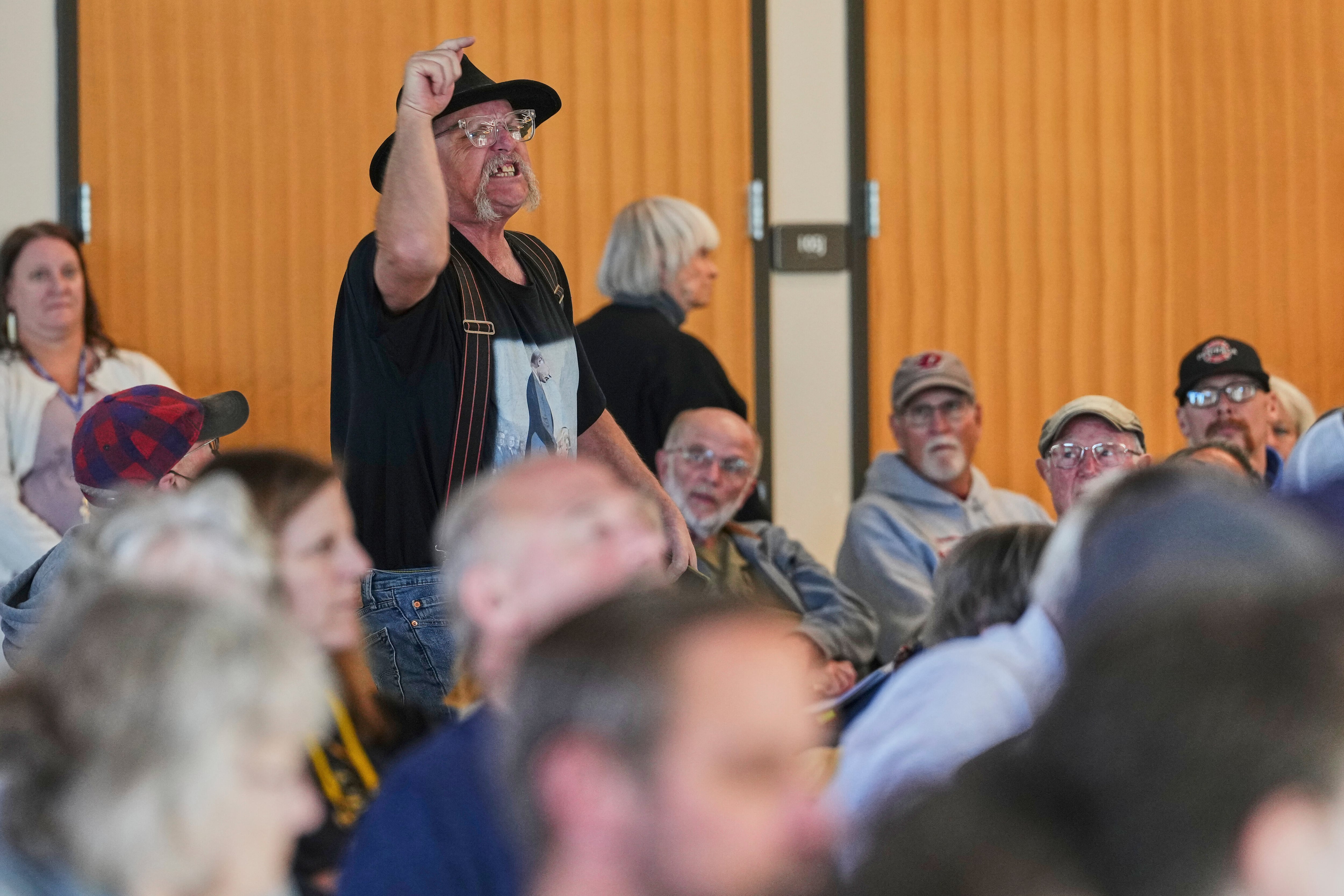 An attendee stands and shouts towards the stage during a town hall event with Rep. Marie Gluesenkamp Perez.