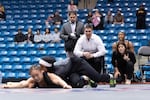 Associate head wrestling coach Christian Flavin (center) and head coach Ashley Flavin (right) watch intently as Zaynah McBryde competes.