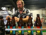 Double Mountain Brewery founder Matt Swihart grabs freshly bottled pale ale from the bottling line in Hood River. The brewery's new beer is among the first to be sold in Oregon's new refillable beer bottles.