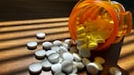 A pill bottle with white tablets spilling out is shown.