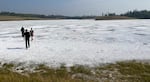 Members of the research team walk across the surface of Last Chance Lake in September 2022. At the end of the summer, the water has almost all evaporated, leaving a salty crust on the surface. But water persists below in pockets and hollows, and soft sediments sit beneath, creating a somewhat treacherous crème brûlée structure to walk on.