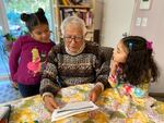 Amayah and Yara, Karen Perez-Da Silva's daughters, look at schoolwork with Perez-Da Silva's father. While Amayah and Yara want to return to school, they will finish the year in distance learning out of safety concerns for their grandparents and Yara, who has asthma.