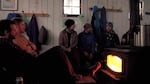 Backcountry skiers staying warm by the woodstove inside the Tilly Jane A-frame.