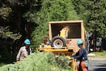 Workers with the Kittitas County Fuels Crew throw vegetation into a wood chipper near Roslyn, Wash.