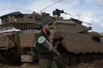 An Israeli soldier carries a tank shell at a staging area in southern Israel, near the border with Gaza, on Thursday, Feb. 1.