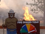 Fire burns near a Smokey the Bear fire warning sign as the Oak Fire burns through the area on July 24, 2022 near Jerseydale, California.