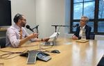 A man and a woman speak across a conference room table.