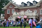 A mob stands outside the Governor's Mansion after getting through a perimeter fence, Wednesday, Jan. 6, 2021, at the Capitol in Olympia, Wash. The area was eventually cleared by police. 