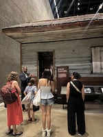 Students stand outside the Point of Pines cabin at the National Museum of African American History and Culture.