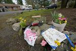 Flowers and signs sit atop some rocks as memorial to the victims in the Atlanta attacks. One of the signs partially reads "WE STAND WITH OUT NEIGHBORS" with a drawn heart on it.