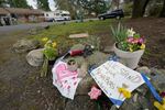 Flowers and signs sit atop some rocks as  memorial to the victims in the Atlanta attacks. One of the signs partially reads "WE STAND WITH OUT NEIGHBORS" with a drawn heart on it.