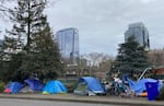 FILE: People camp in tents next to the Interstate 405 freeway in Portland, Ore., on March 31, 2023.