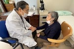 Dr. Masao Tomonaga takes the pulse of an atomic bomb survivor at a care home in Nagasaki, Japan.