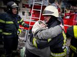 In this photo released by Ukrainian State Emergency Service, a firefighter hugs an elderly woman after evacuation from an apartment building hit by shelling in Kyiv, Ukraine, Monday, March 14, 2022. (Ukrainian State Emergency Service via AP)