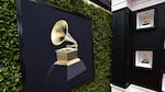 A framed picture of a gramophone against a black background hangs on what appears to be a hedge.