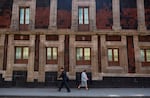 FILE - Pedestrians walk past a slightly tilted historic building in downtown Mexico City,  June 15, 2016. The city was built on a drained lake bed and many buildings are noticeably tilted, from sinking unevenly into the soft earth over decades or centuries.
