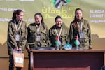 Four Israeli hostages stand on a stage before Hamas fighters hand them over to a team from the Red Cross in Gaza City on Saturday.