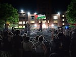 A man holds up a Palestinian flag as activists and students surround piled barricades at an encampment at at George Washington University early Monday.
