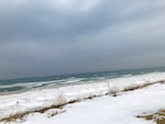 The snowy shoreline of Lake Michigan on a day with dark gray clouds.