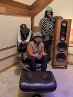 Logan Richardson seated, Joe Sanders leaning on a chair and Justin Brown leaning on an upright studio monitor