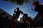 Children are shown playing with ring toys against a blue sky.