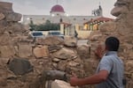 A man looks through a gap in a stone wall toward a Greek Orthodox church where gunmen opened fire during a funeral hours earlier in Hamoud village, in Jordan's Karak governorate on Friday.