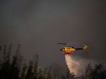 A helicopter drops water near Varnava village during a wildfire, north of Athens, Greece, on Sunday, with many regions of the country on high alert due to high temperatures and wind speeds.