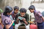 A. Santhos inserts a slide into the Foldscope. He is a former student at Eden School who keeps in touch with the students of his alma mater, taking them for nature walks to examine the world around them with the paper microscope.